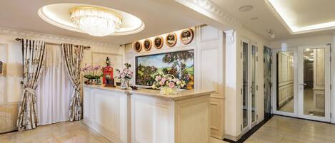A spacious kitchen with a central island, a chandelier, and a television above it.