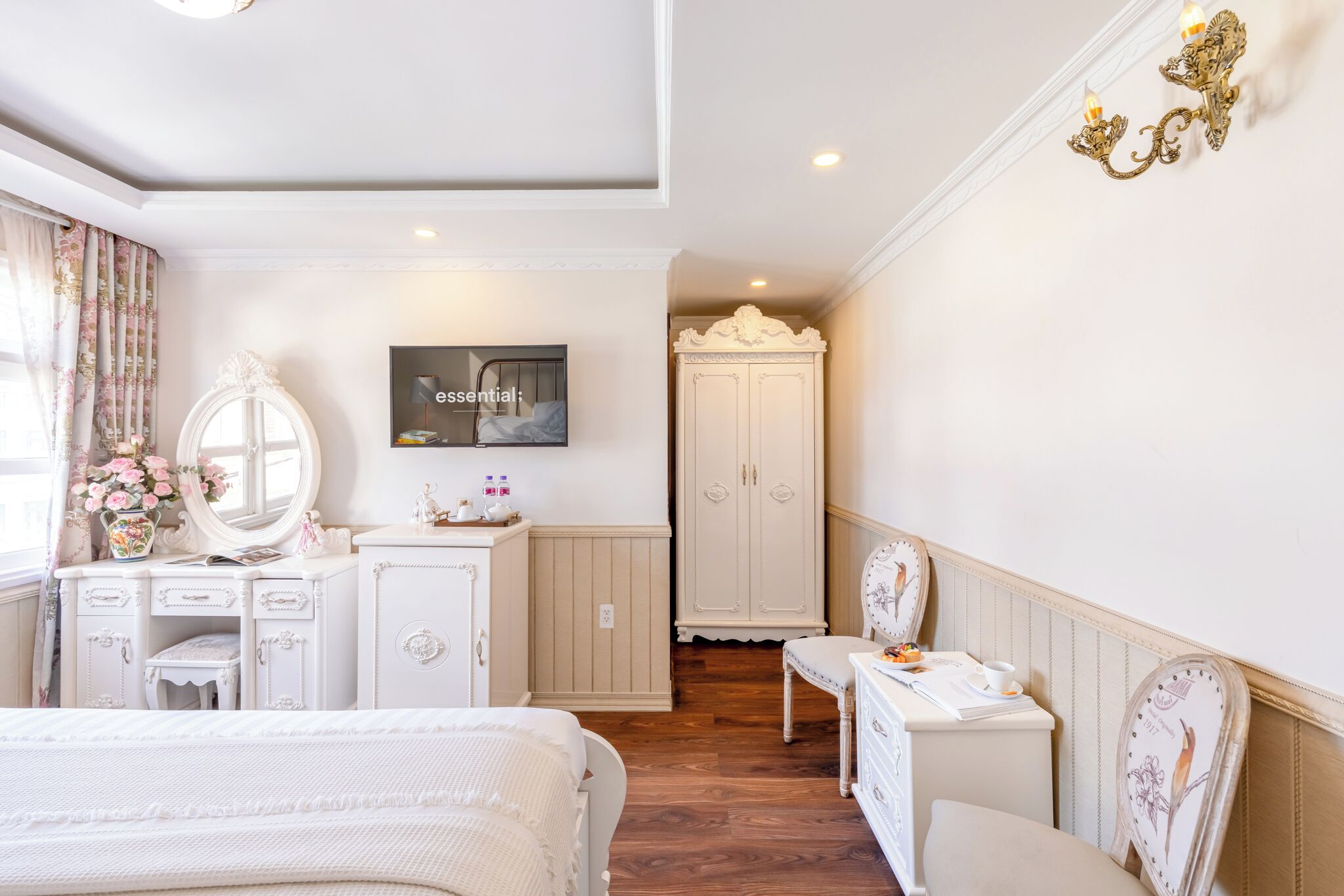 Ein Schlafzimmer mit Bett, Kommode, Schminktisch und Fernseher an der Wand.