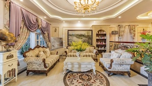 A luxurious living room with ornate furniture, a chandelier, and a large painting. - Hoa Sen Vang (Xuan Huong - Da Lat)