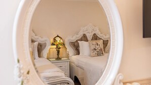 A bedroom with a large ornate mirror, a bedside table with a lamp, a bed with floral pillows, and a small decorative item on the dresser. - Hoa Sen Vang (Xuan Huong - Da Lat)