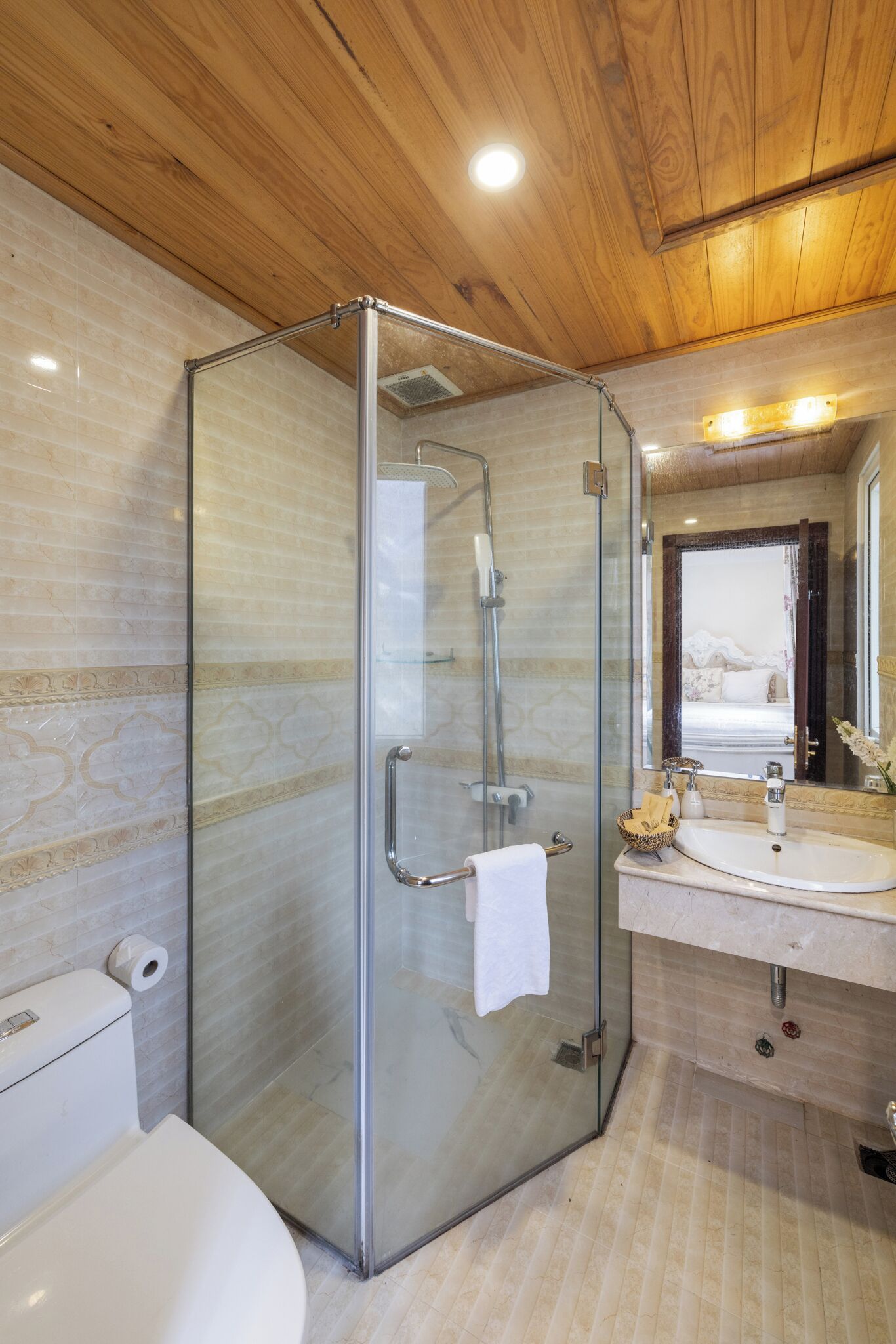 A modern bathroom with a glass-enclosed shower, a white toilet, and a sink with a mirror.