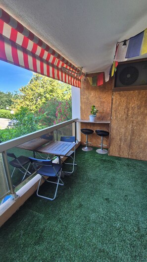 A balcony with a table and chairs, a small stool, a potted plant, and a wooden cabinet. - Apartment 2 rooms 45m2 quartier Saint Jean ANTIBES (Antibes)