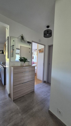 A modern kitchen with a wooden cabinet, a potted plant, and a mirror. - Apartment 2 rooms 45m2 quartier Saint Jean ANTIBES (Antibes)