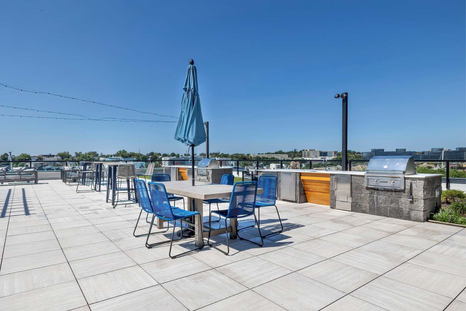 An outdoor patio with a table and chairs, a grill, and a view of the city skyline.