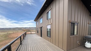 Ein Gebäude mit einer Terrasse, großen Fenstern und Blick auf eine Landschaft.