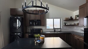 Eine moderne Küche mit einer zentralen Kochinsel, Holzschränken, einem Backofen und einem großen Fenster.