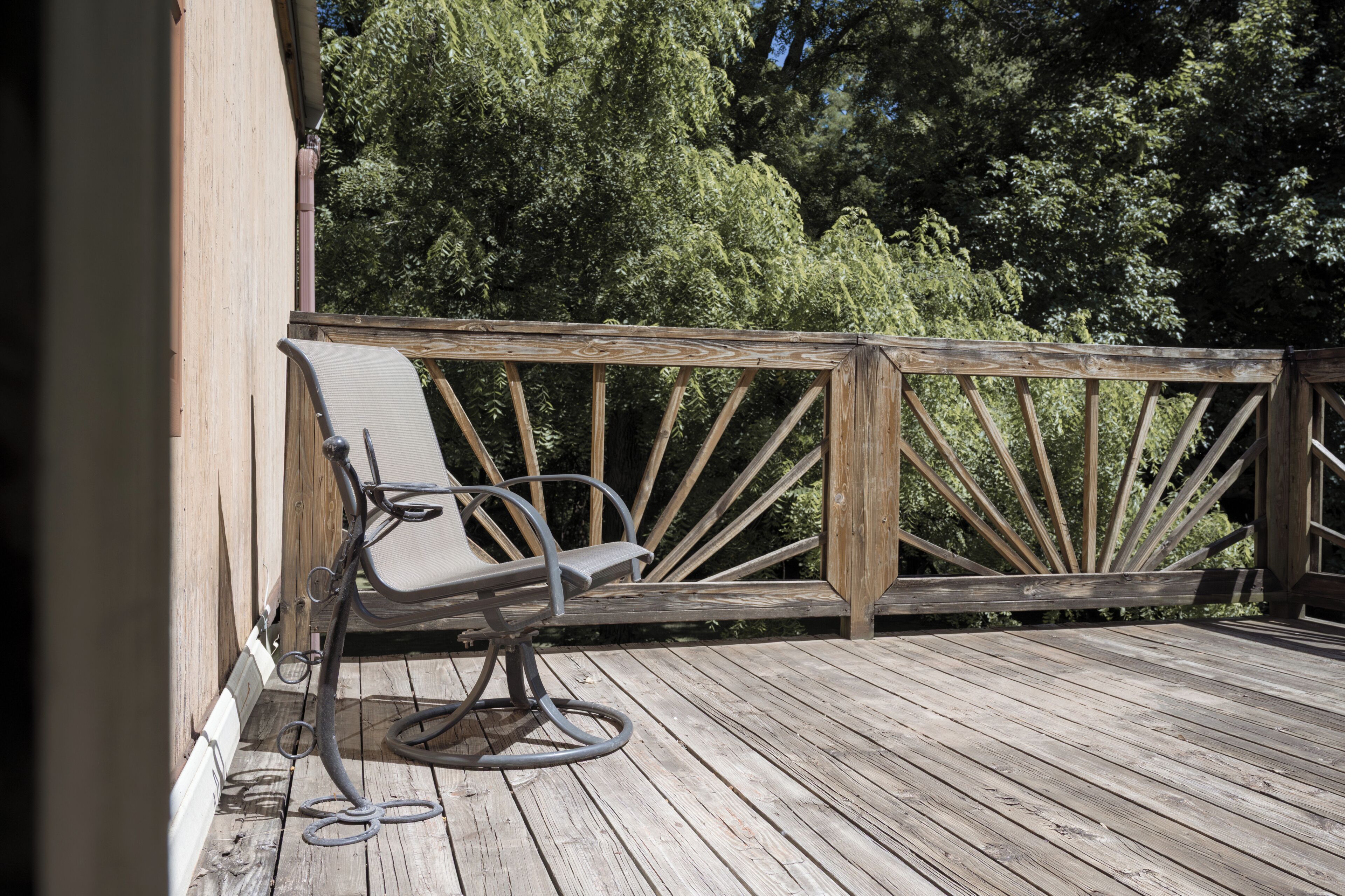 A wooden deck with a metal chair and a metal railing.
