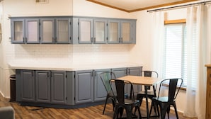 A kitchen with grey cabinets, a white countertop, and a dining area with a table and chairs.