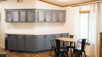 A kitchen with grey cabinets, a white countertop, and a dining area with a table and chairs.