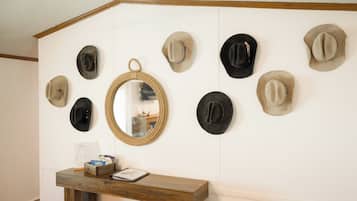 A wall with multiple hats and a mirror.