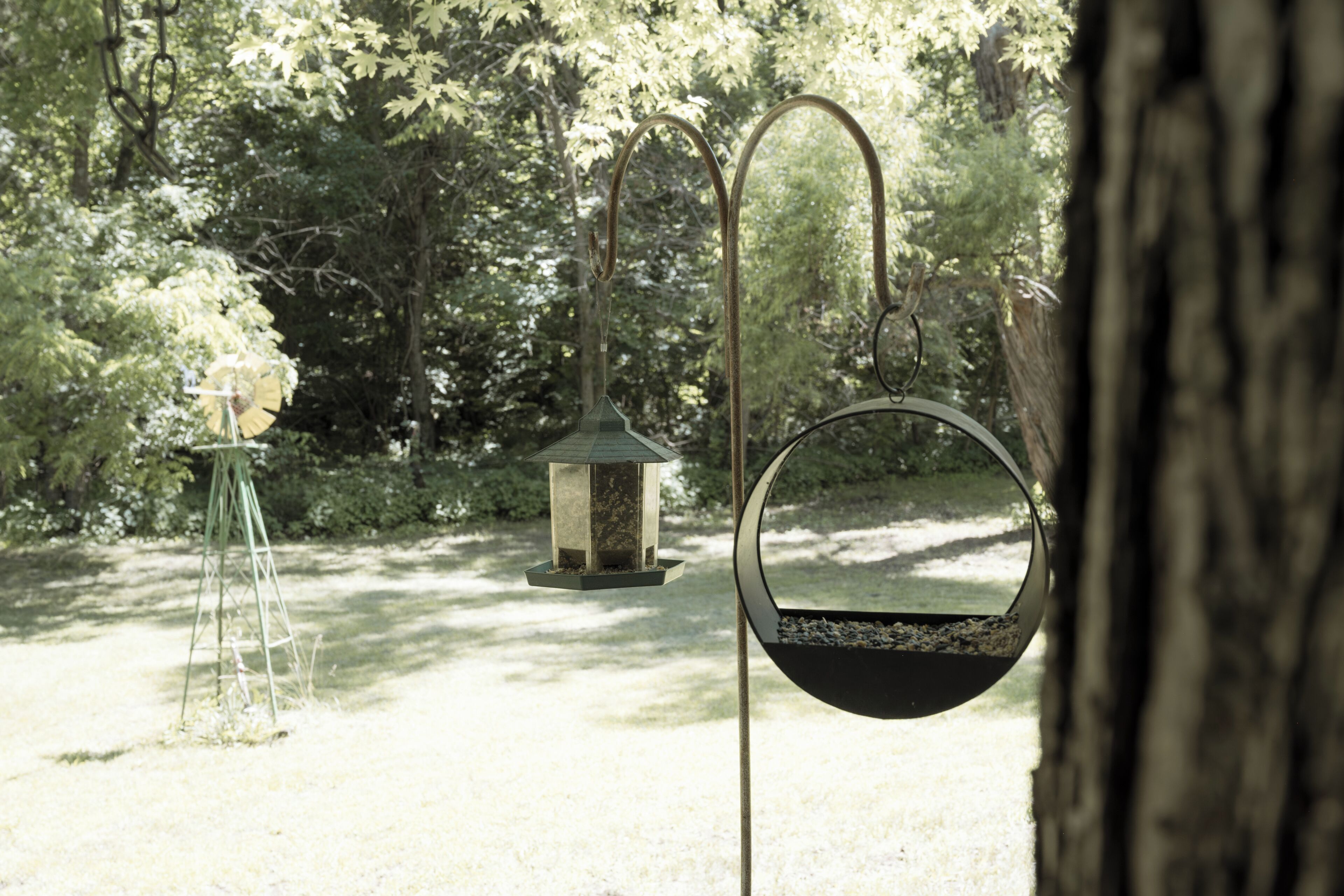 A garden with a hanging bird feeder, a lantern, and a swing set.