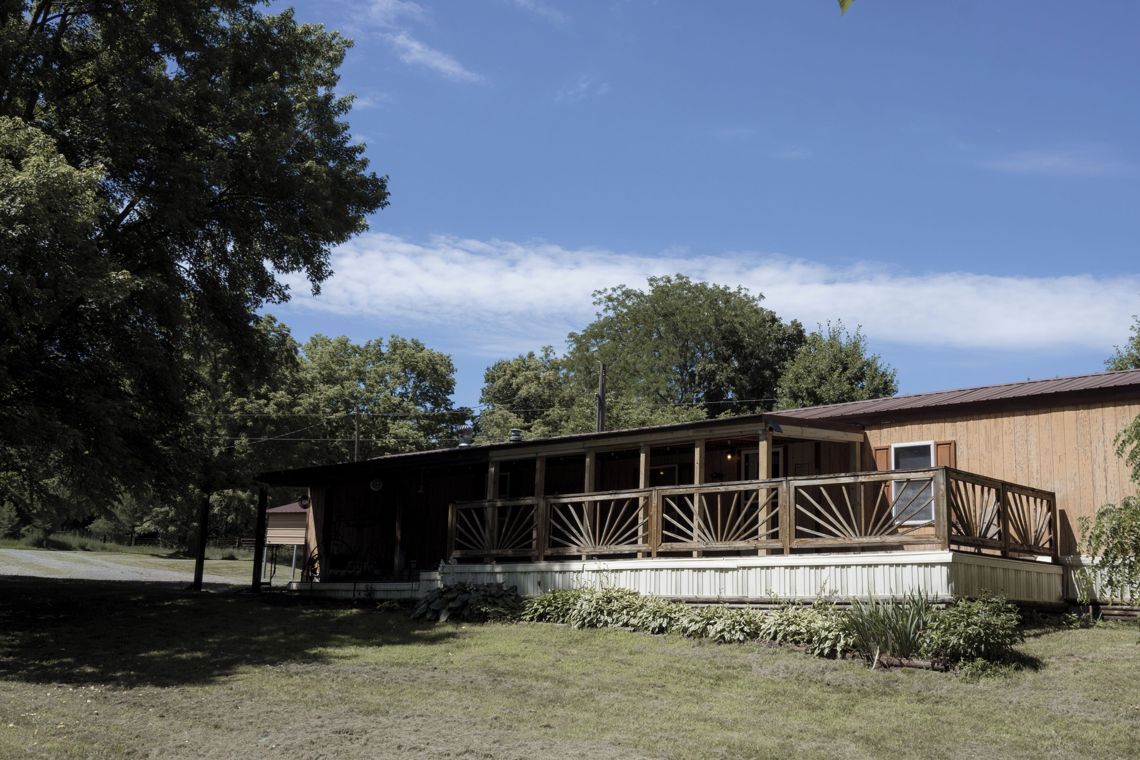 A wooden building with a covered porch and a fenced area.