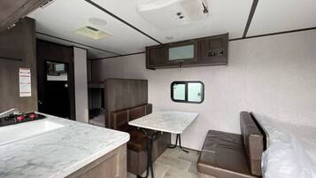 A compact RV kitchen with a sink, stove, and a small window.
