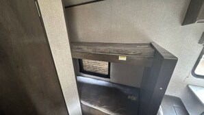 Een stapelbed met een raam, een klein plankje en een deur.