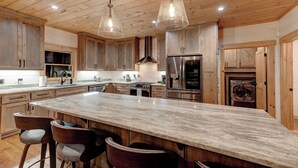 Une cuisine spacieuse avec des meubles en bois, un grand îlot en marbre et des appareils électroménagers modernes.
