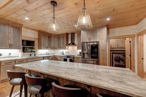 A spacious kitchen with wooden cabinets, a large marble island, and modern appliances. - Spacious 4-bedroom mountain view in Ellijay with private hot tub and pool table (Ellijay)