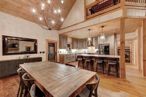 Una cocina amplia con armarios de madera, una isla grande con taburetes de bar y una lámpara colgante.