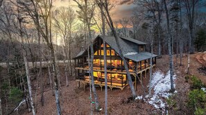 A cabin with multiple levels, surrounded by trees, and accessible via a dirt path. - Spacious 4-bedroom mountain view in Ellijay with private hot tub and pool table (Ellijay)
