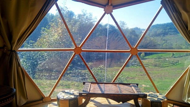 Una carpa con piso de madera, una mesa y vistas a un paisaje montañoso.