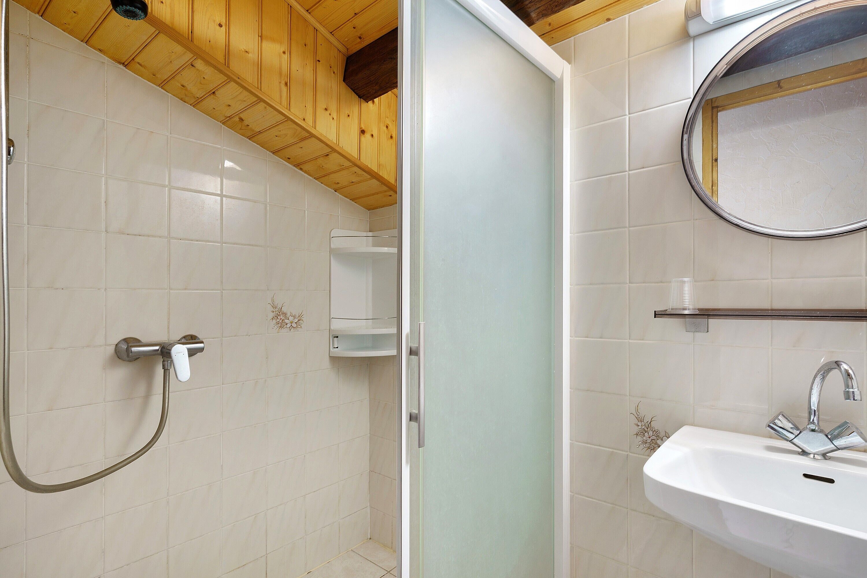 A bathroom with a shower, a sink, and a mirror.