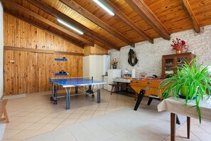 Una habitación con mesa de ping pong, mesa de fútbol y techo de madera.