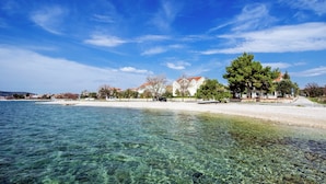 Una zona costera con agua cristalina, una playa arenosa y edificios con techos rojos.
