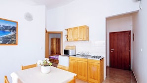 Una cocina compacta con armarios de madera, un microondas y un lavabo.