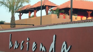 Un letrero con la palabra 'hacienda' en una pared, rodeado de pilares y palmeras.
