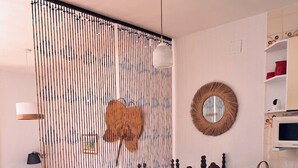 Een eethoek met een ronde tafel, houten stoelen, een decoratief wandpaneel, een hanglamp en een magnetron.
