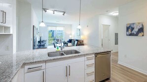 A modern kitchen with granite countertops, a built-in dishwasher, and pendant lighting.