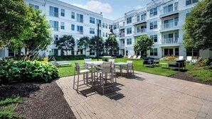 A courtyard with outdoor seating, a brick patio, and a multi-story building with balconies.