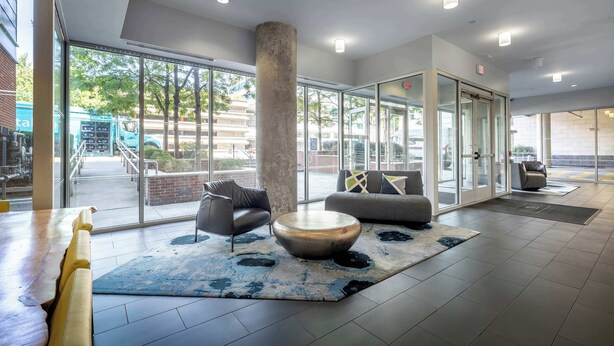 A modern lobby with a large glass door, a round coffee table, and a sofa.