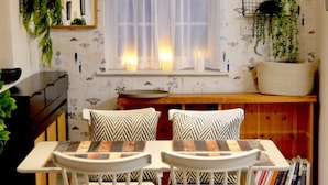 A dining area with a table and chairs, a window with curtains, and a bookshelf with books. - The Stables in Central Horncastle - Pass the Keys (Horncastle)