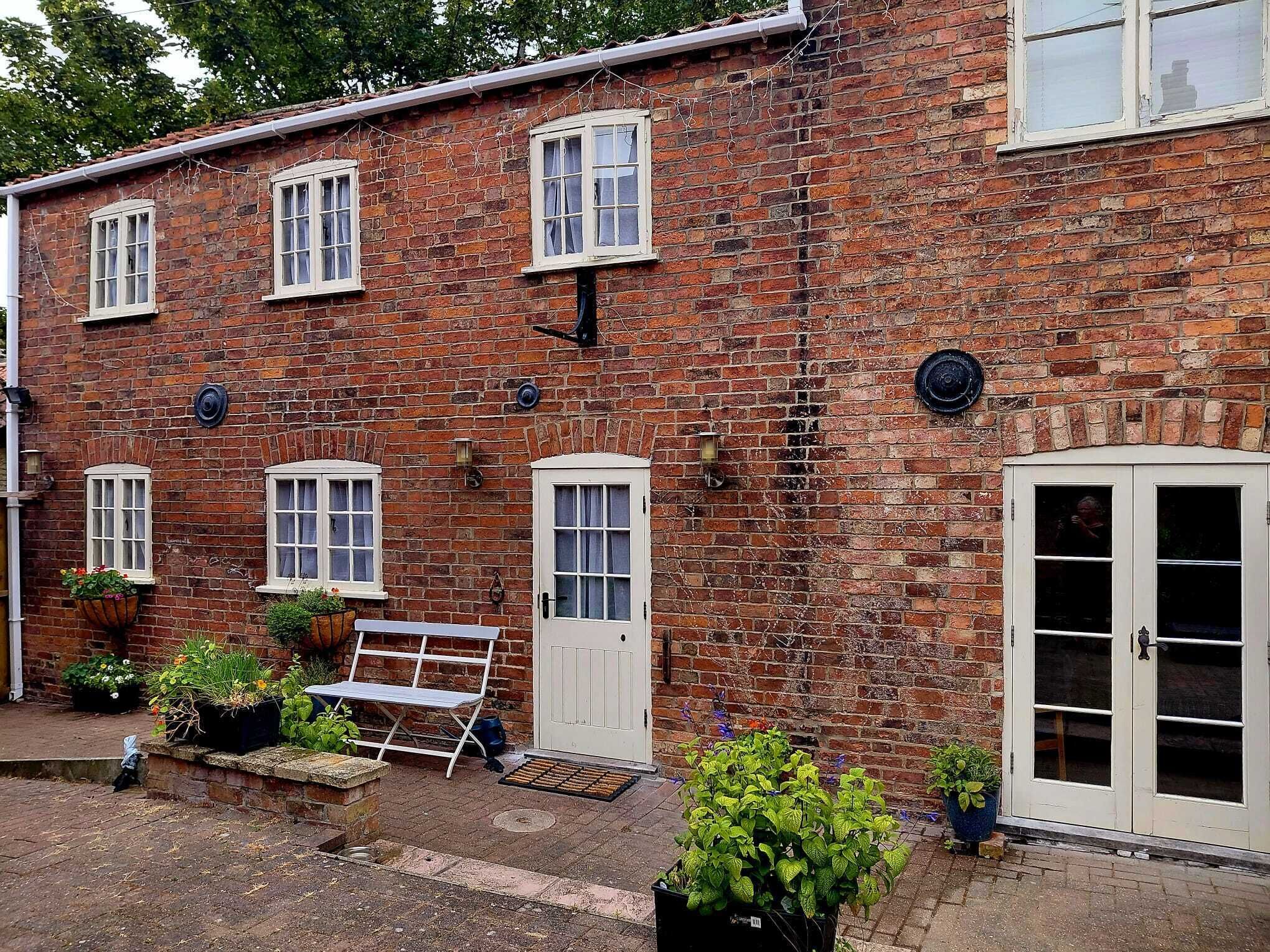 A brick building with multiple windows, a white door, and outdoor seating.