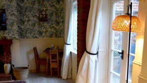 A room with a wooden floor, a patterned rug, a table with chairs, a lamp, and a window with curtains. - The Stables in Central Horncastle - Pass the Keys (Horncastle)