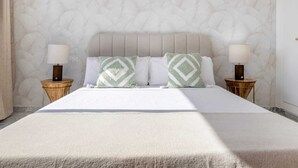Una habitación de hotel con una cama, dos mesitas de noche y un papel tapiz estampado.
