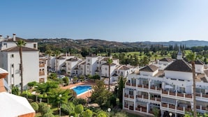 Zona residencial con edificios blancos, una piscina y vistas a colinas.