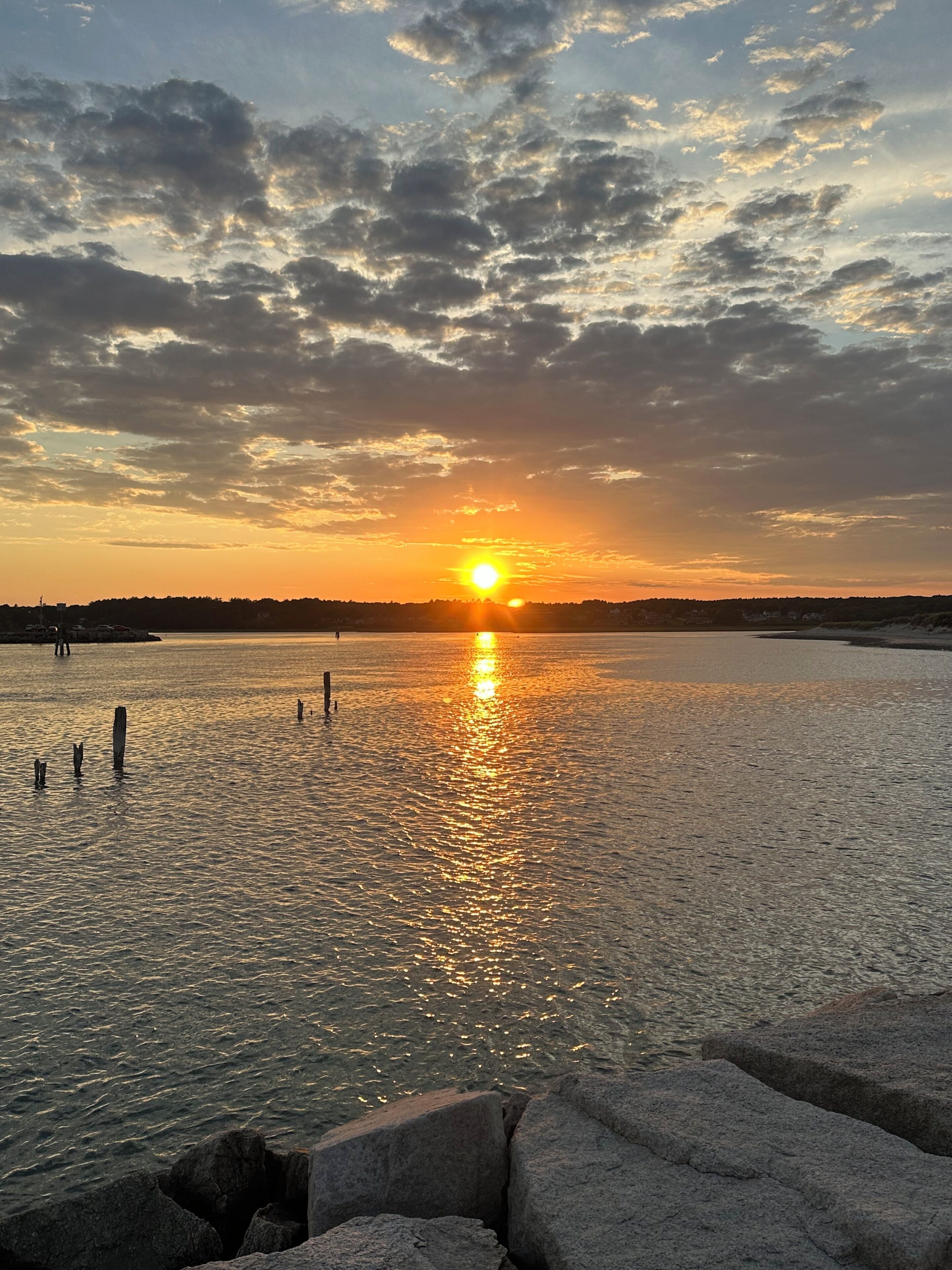 A sunset over a calm body of water with a rocky foreground.