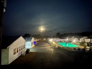 A nighttime view of a residential area with houses, a swimming pool, and a street.