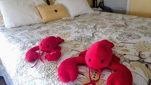 A bed with a floral-patterned bedspread, two red plush toys, and a yellow pillow.