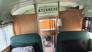 Um espaço interior compacto com duas camas, um pequeno ventilador e uma placa com a inscrição 'MATCHHEAD'.
