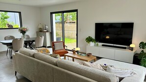 A modern living room with a sofa, TV, dining table, chairs, and a view of the outdoors. - Ti Pépin - Contemporary house - 5 min from the beach - Rated 3* furnished for tourism (Fouesnant)