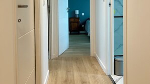 A hallway with wooden flooring, white walls, and a blue room in the distance. - Ti Pépin - Contemporary house - 5 min from the beach - Rated 3* furnished for tourism (Fouesnant)
