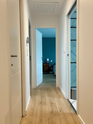 A hallway with wooden flooring, white walls, and a blue room in the distance. - Ti Pépin - Contemporary house - 5 min from the beach - Rated 3* furnished for tourism (Fouesnant)