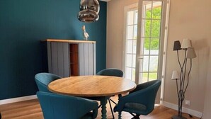En matplats med ett runt träbord, fyra blå stolar, ett högt skåp och en golvlampa.