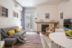 A living room with a sofa, a fireplace, a television, and a dining area. - GP23 Apartment - Renew apartment close to the sea and downtown Alghero (Alghero)