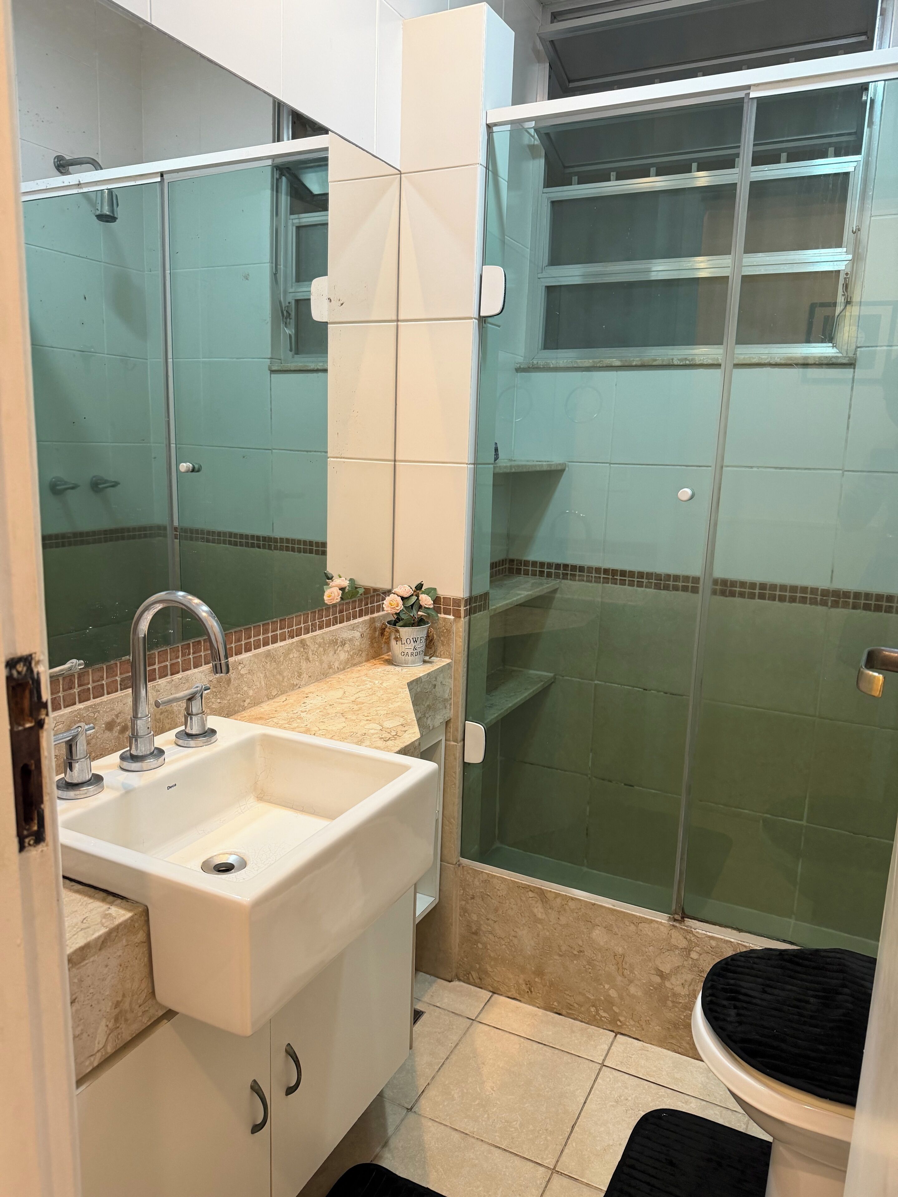 A bathroom with a sink, mirror, shower, and toilet.
