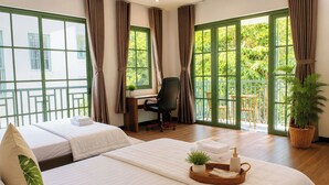 Ein Hotelzimmer mit zwei Betten, einem Schreibtisch, einem Stuhl und großen Fenstern mit Vorhängen.