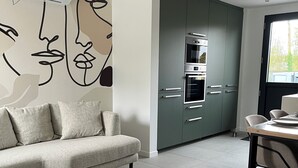 A modern living room with a sofa, a coffee table, and a dining area with a table and chairs. - Le pressoir, calm and nature - 5min Honfleur (Équemauville)