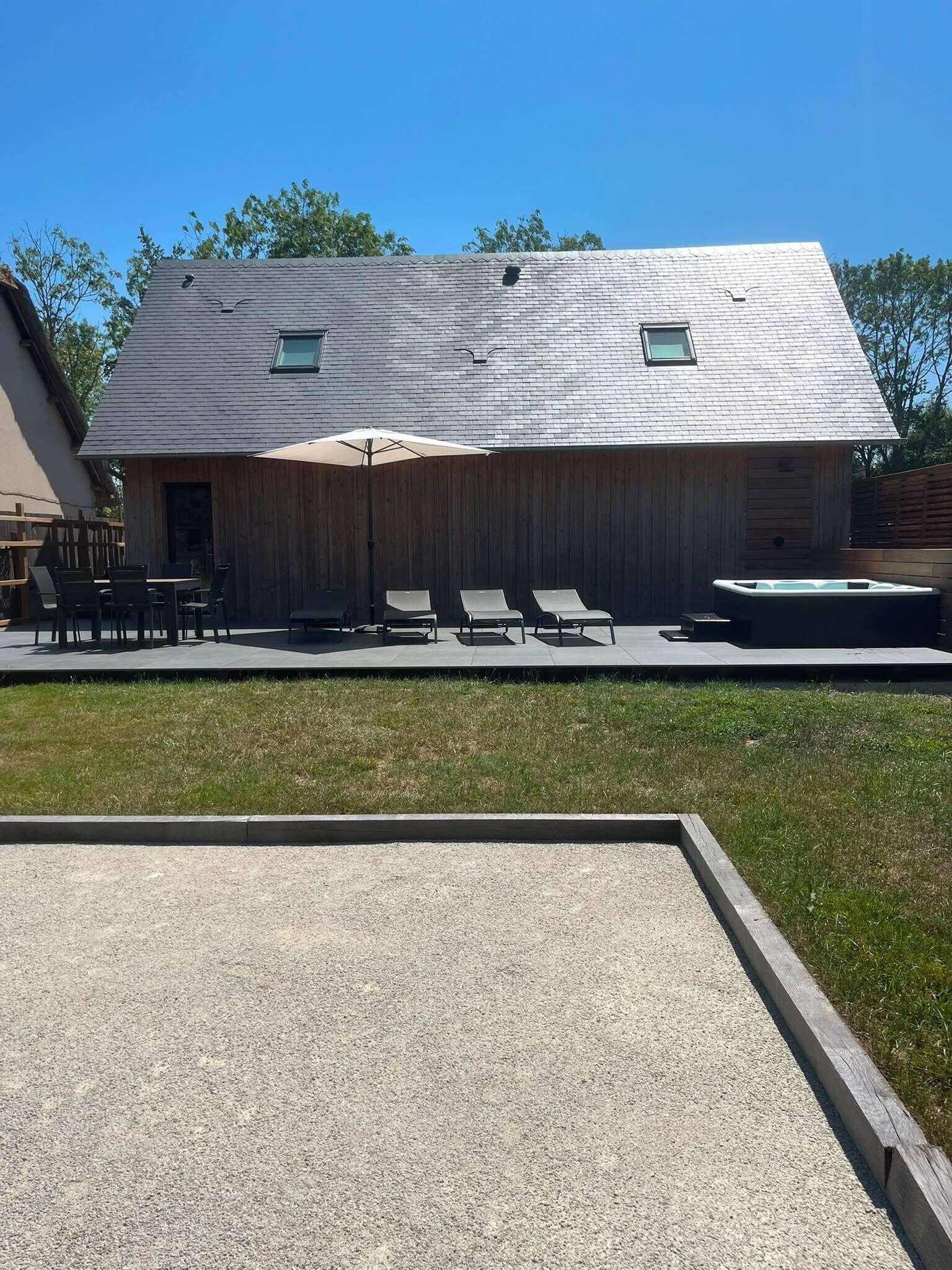 A house with a patio area featuring outdoor furniture and a hot tub.